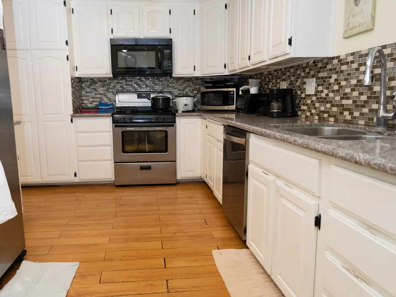 Accessible kitchen with white cabinetry, granite counters, and modern appliances in residential care facility
