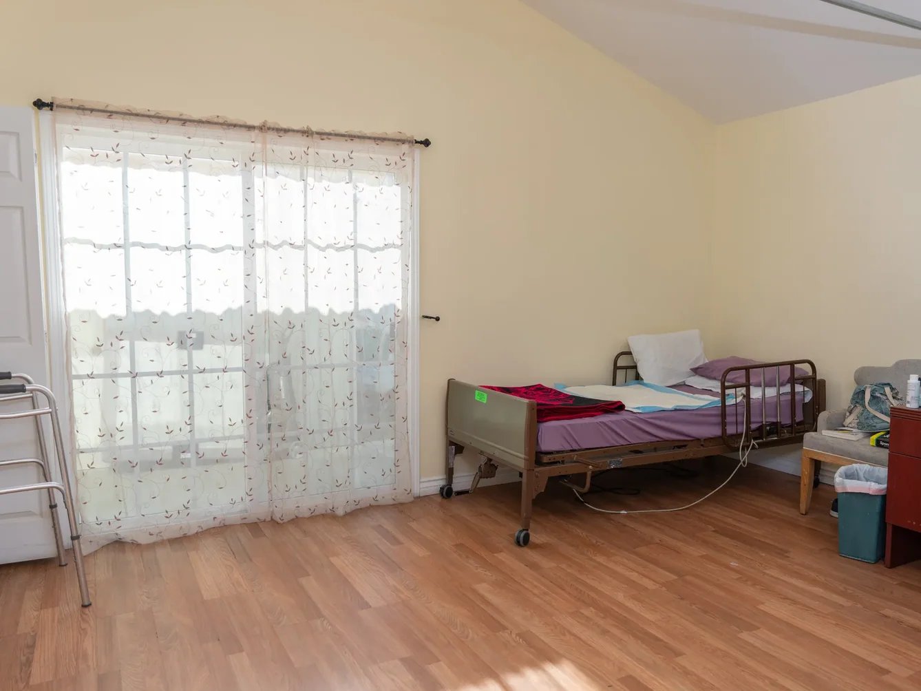 Spacious accessible bedroom with hospital bed, wheelchair access, and natural lighting for residential care