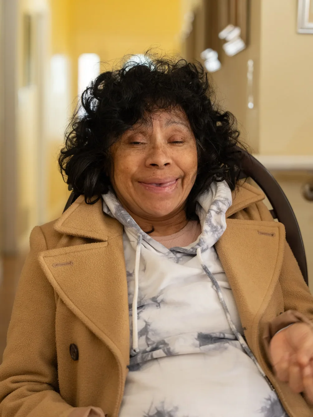 Happy senior resident smiling at camera while seated comfortably in care facility common area