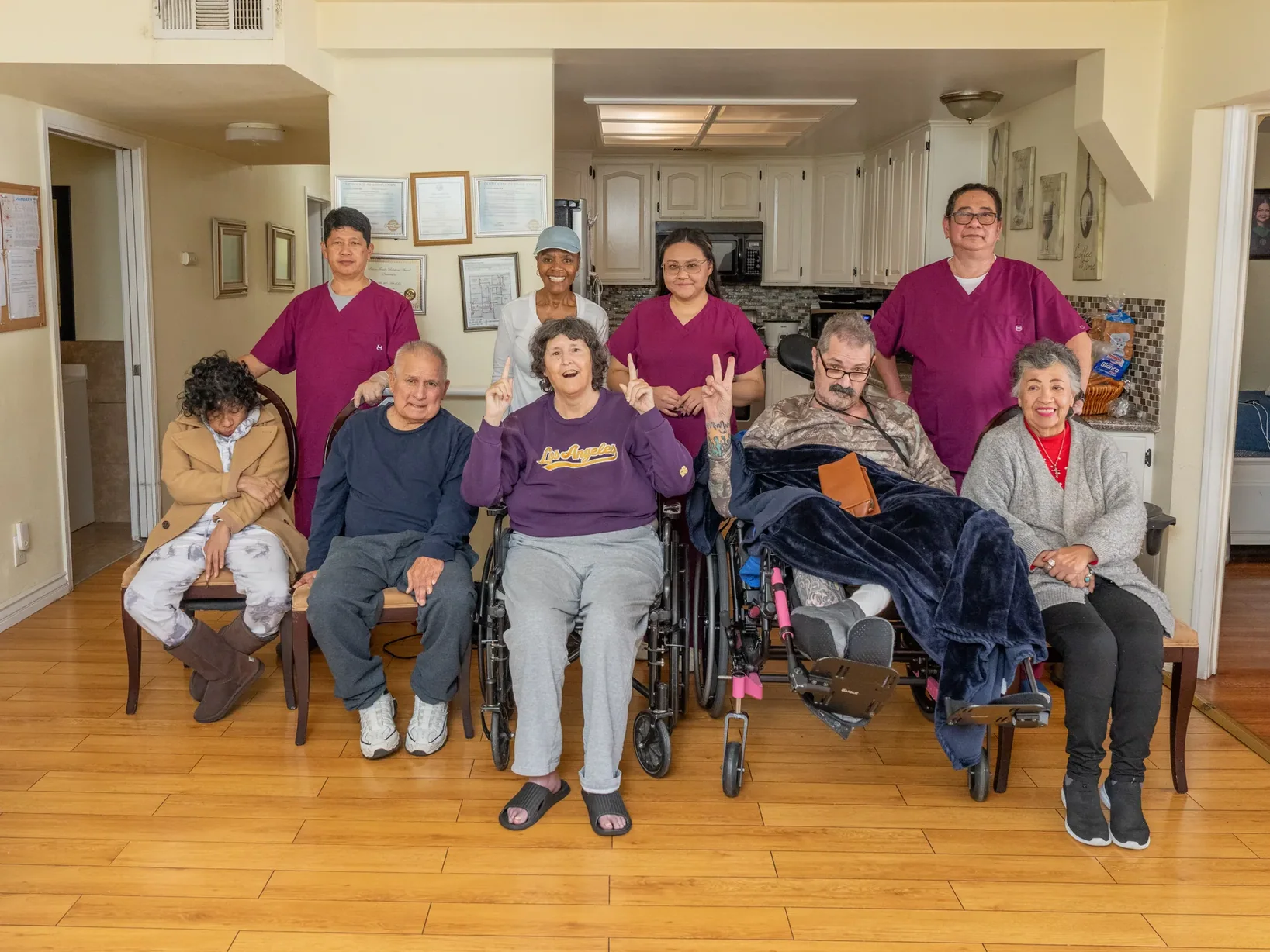 Residents and caregivers posing together as a group in the comfortable living area of the care home